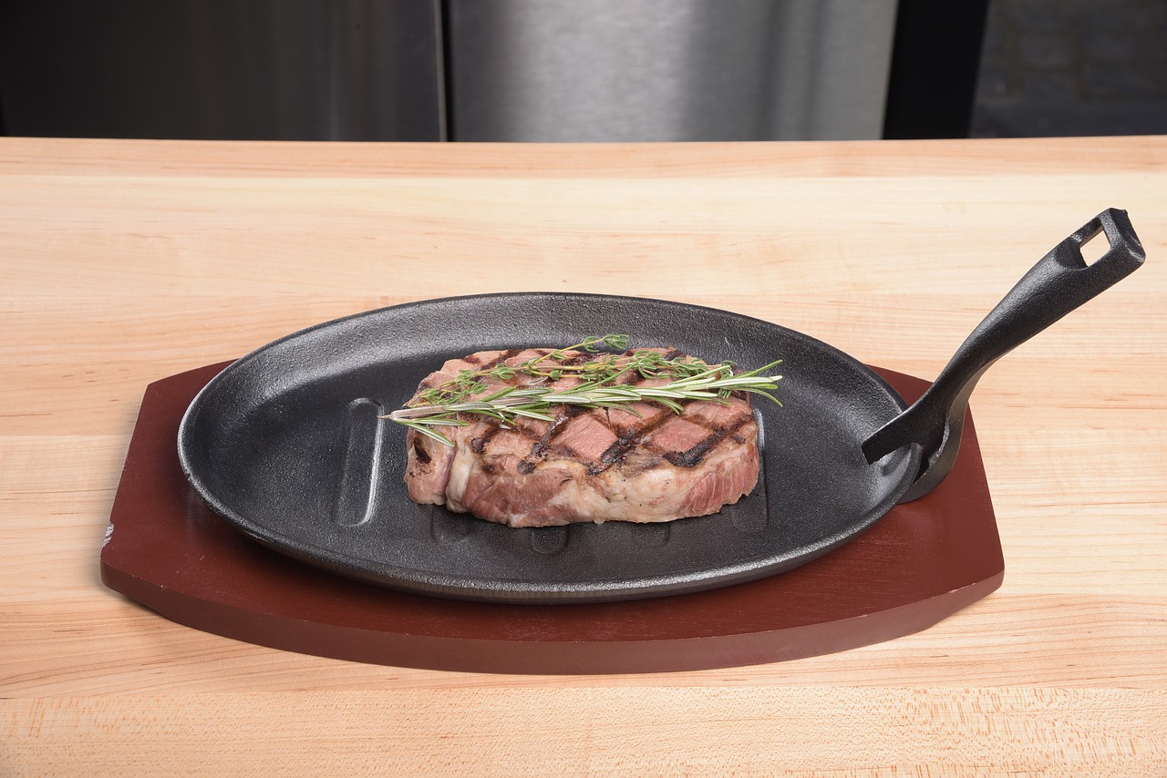 Image of Grilled Garlic and Herb Steak with Chimichurri Sauce on a platter "Grilled ribeye steak topped with vibrant chimichurri sauce, garnished with fresh herbs." Close-up of Chimichurri Sauce in a small bowl "Fresh chimichurri sauce made with parsley, cilantro, garlic, and red wine vinegar, ready to serve." Image of ribeye steaks marinating with garlic and herbs "Ribeye steaks marinating with a mixture of minced garlic, rosemary, thyme, and olive oil for enhanced flavor." Grilled steak slices on a cutting board with chimichurri drizzle "Juicy grilled steak slices on a wooden board, drizzled with fresh chimichurri sauce." Side dishes of roasted potatoes and grilled asparagus with steak "A complete meal with grilled garlic and herb steak, roasted potatoes, and grilled asparagus." Image of steak grilling on a hot grill "Ribeye steaks grilling to perfection on a hot outdoor barbecue, ready for serving." Finished plated meal with steak, chimichurri sauce, and garnishes "A delicious grilled garlic and herb steak served with chimichurri sauce