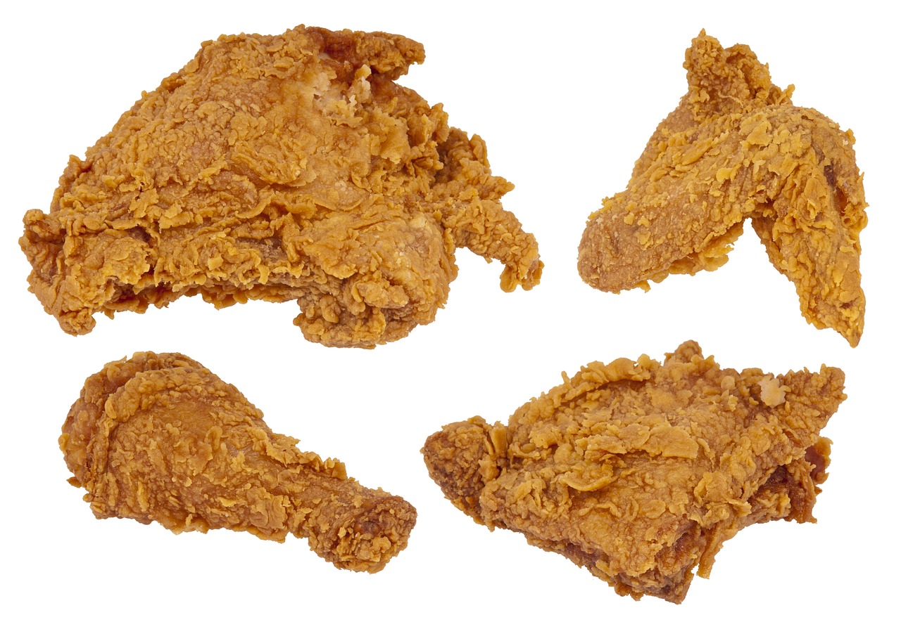 Golden-brown KFC-style fried chicken pieces, crispy on the outside and juicy on the inside, served on a rustic wooden platter with a side of dipping sauce