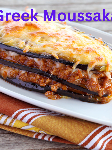 A delicious slice of Greek Moussaka with golden BΓ©chamel topping, layered with roasted eggplant, potatoes, and savory meat sauce, served on a white plate